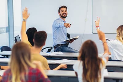 students in classroom raising hands
