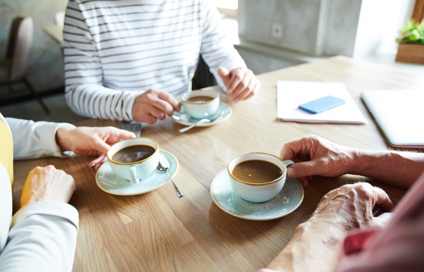 adults meeting around a table with coffee