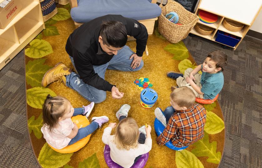 Four children and teacher sitting in circle on rug at FVTC Child Care Center