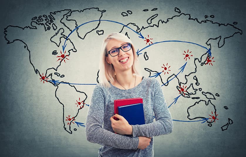 Female in front of world map holding books