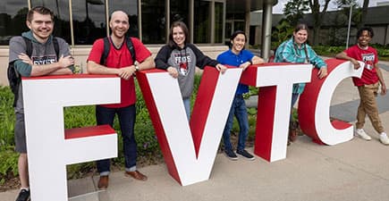 students standing by FVTC letters