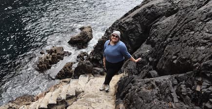 person standing near the water on some rocks