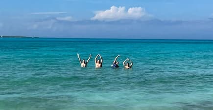 four people standing in the ocean